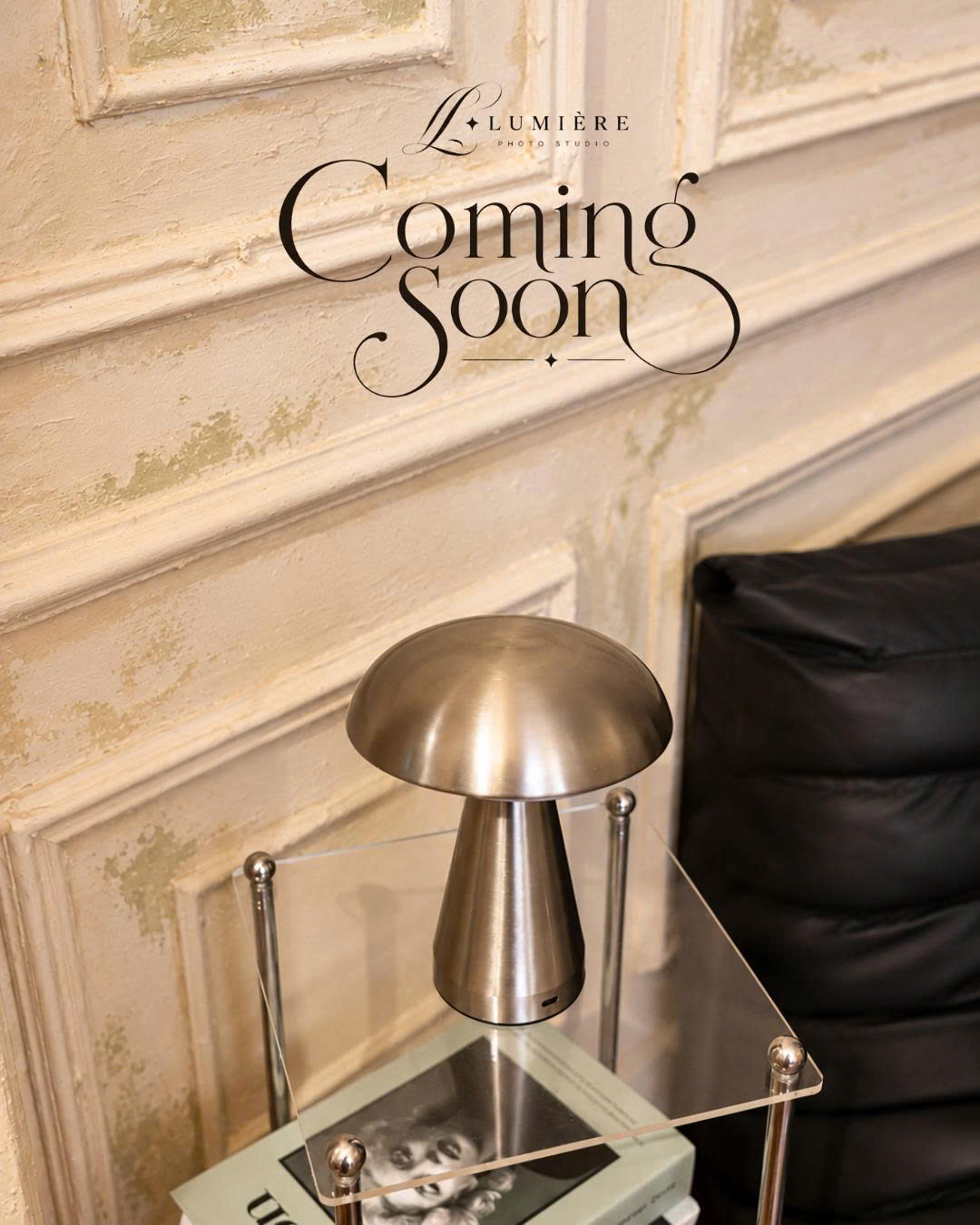 Đèn bàn kim loại bên ghế đen và tường cổ điển, poster Coming Soon Lumière